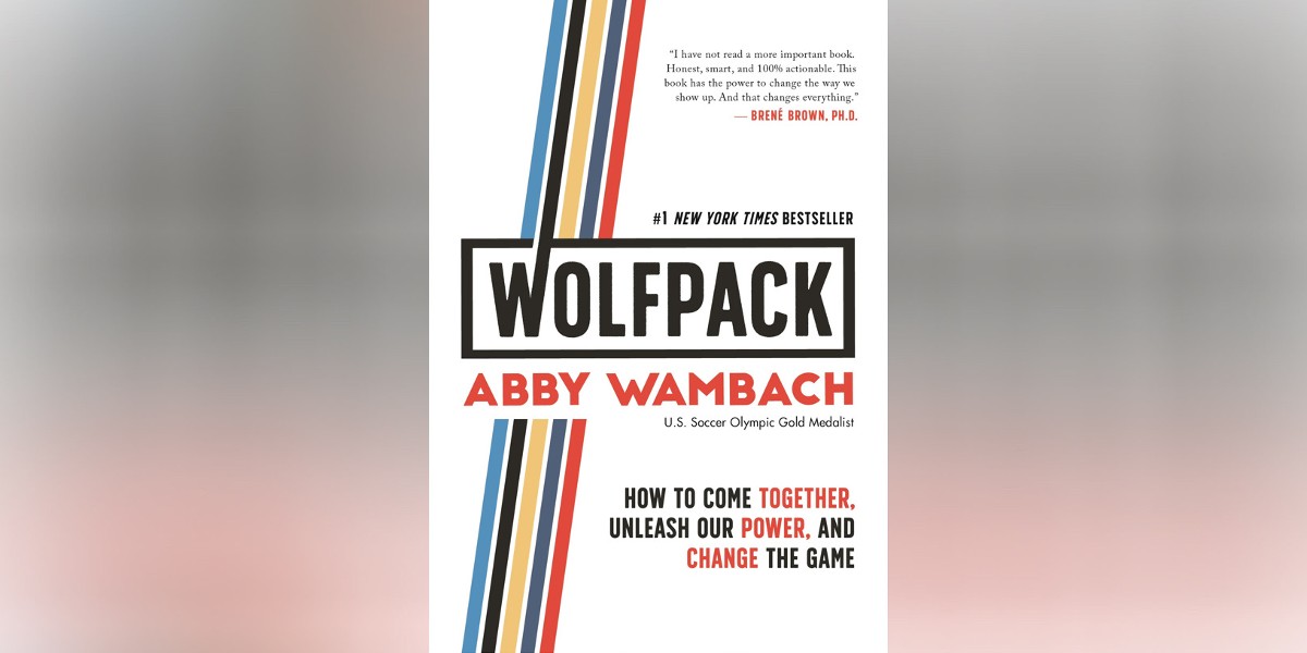 The cover of Wolfpack by Abby Wambach is white with black and red letters. A stripe in light blue, black, gold, dark blue, and red runs diagonally across it behind the words.