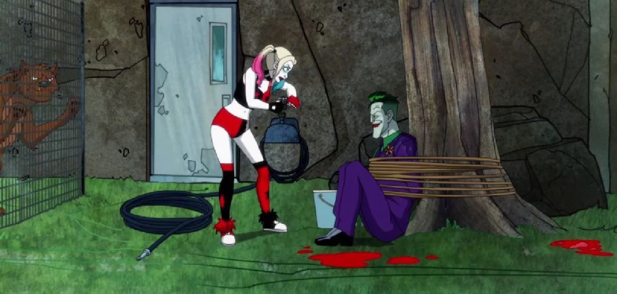 Harley stands over Joker, who's tied to a tree, while blood splatters are on the grass around them and a hyena exhibit is behind them in Harley Quinn Season 4 Episode 10, "Killer's Block."
