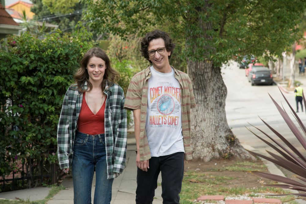 Mickey and Gus walk down a sidewalk in a residential neighborhood of LA in the Netflix series Love. 