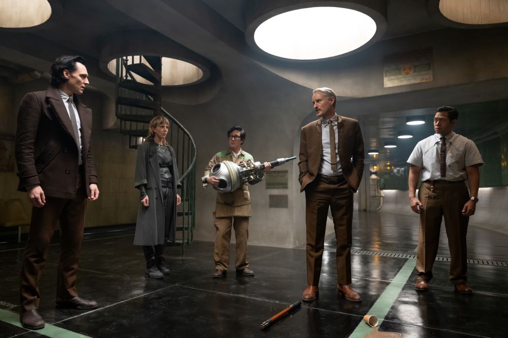 Loki, Sylvie, O.B., Mobius and Casey stand in a dimly lit hallway of the Time Variance Authority building while looking serious in Loki Season 2 Episode 4, "Heart of the TVA."