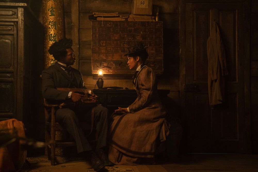 Victor Timely sits with Ravonna Renslayer while both wear 19th-century garb in Loki Season 2 Episode 3, "1893."