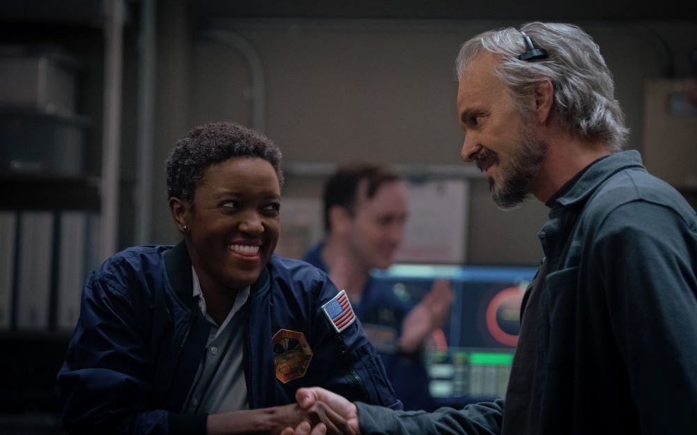 Commander Danielle Poole laughs with Admiral Ed Baldwin while they stand in the mess hall of the Happy Valley base on Mars in For All Mankind Season 4 Episode 2, "Have a Nice Sol."