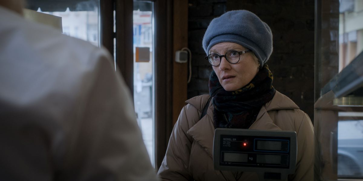 Margo Madison wears a blue beret, scarf and winter coat while standing in a bakery in Moscow in For All Mankind Season 4 Episode 2, "Have a Nice Sol."
