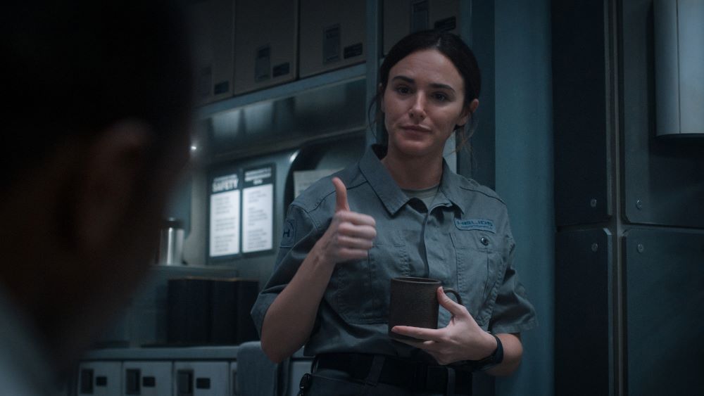 Samantha Massey wears a gray button-down shirt while standing in the employee breakroom of the Happy Valley base on Mars in For All Mankind Season 4 Episode 2, "Have a Nice Sol."