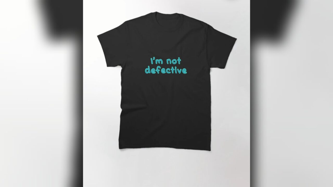 A black t-shirt with the text "I'm not defective" in blue from the Flanaverse series Midnight Club.