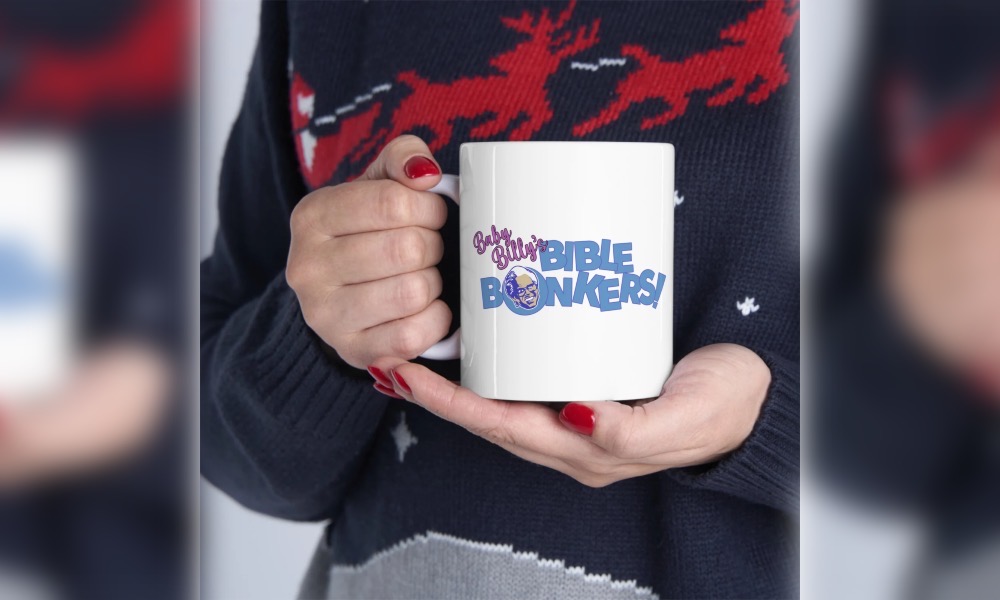 Person in ugly holiday sweater holding a white mug with a picture of an cartoon white man and the words "Baby Billy's Bible Bonkers