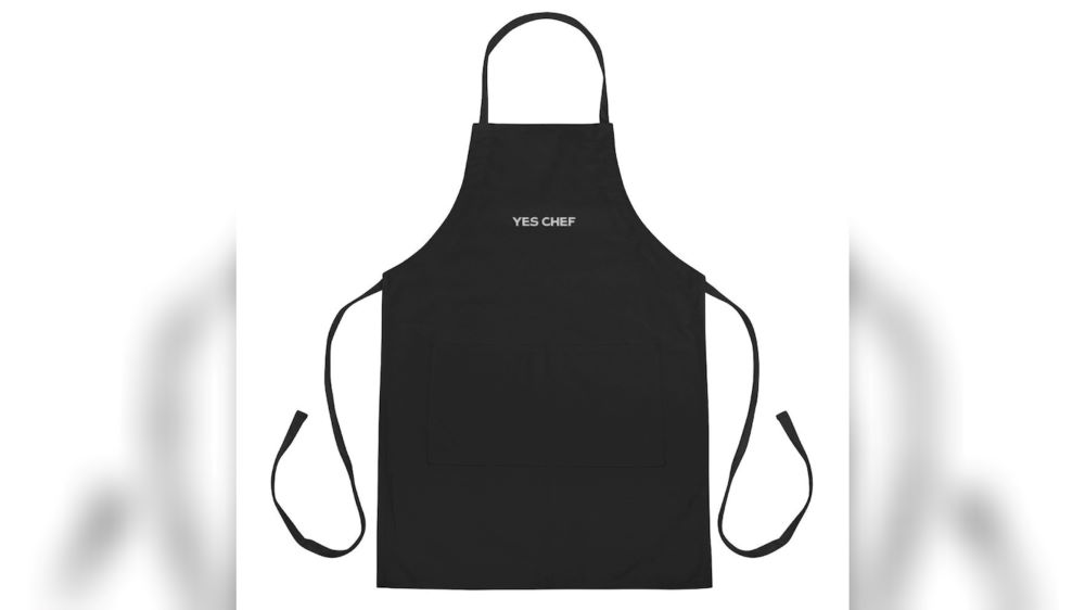 A black apron inspired by the TV series The Bear with "Yes Chef" on the front in white text. 