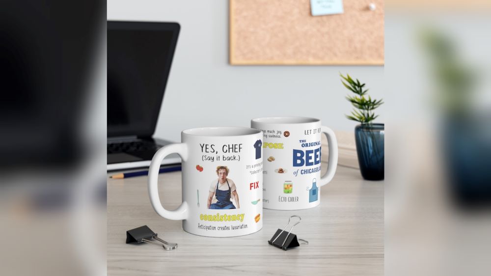 A white mug decorated with icons from the TV series The Bear along with a picture of the main character, Carmy. 
