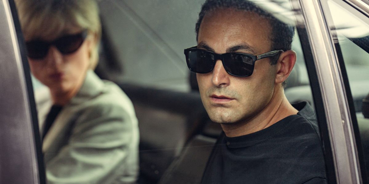 Princess Diana and Dodi Fayed sit in the backseat of a car while wearing black sunglasses in Season 6 of Netflix's The Crown.