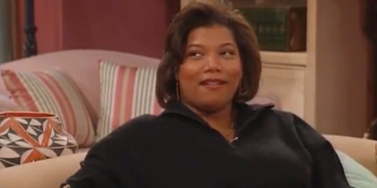 Queen Latifah sitting on a couch wearing a black shirt.