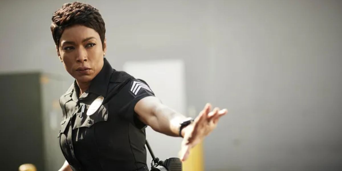 Athena Grant from the series 9-1-1 in her police uniform. She lifts a hand to soothe someone we can't see.