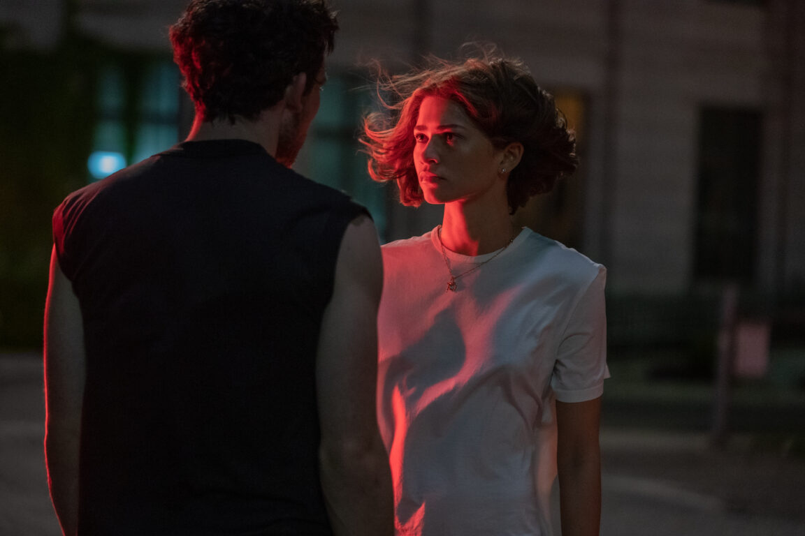 Zendaya stands across from Josh O'Connor as she's bathed in the light of a nearby car in Luca Guadagnino's Challengers.