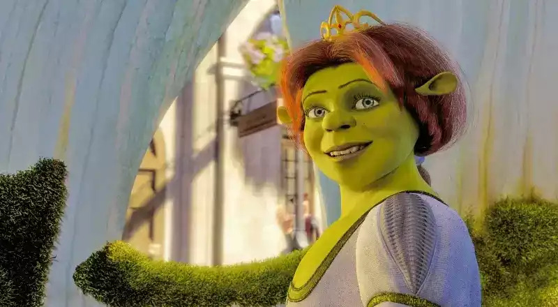 Fiona is dressed in a white gown complete with a golden crown and smiles softly.