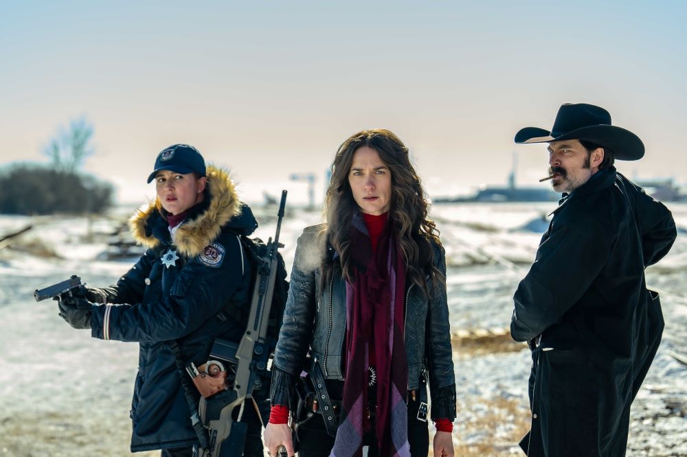 Nicole Haught, Wynonna Earp and Doc Holliday stand in the snow on a sunny day with their weapons drawn, ready to face an unseen threat.