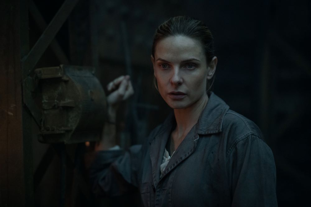 Juliette Nichols wears a jumpsuit while standing in the bottom level of a giant silo in the first season of the TV series Silo.