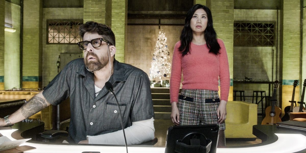 Harry sitting in front of the computer while Mel stands behind him in the cave decorated by a Christmas tree on The Equalizer. 