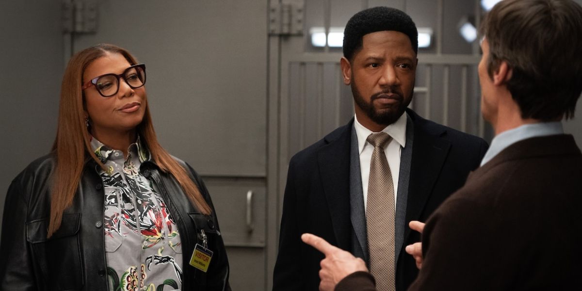 Robyn wearing glasses while standing next to Dante as they talk to another man.