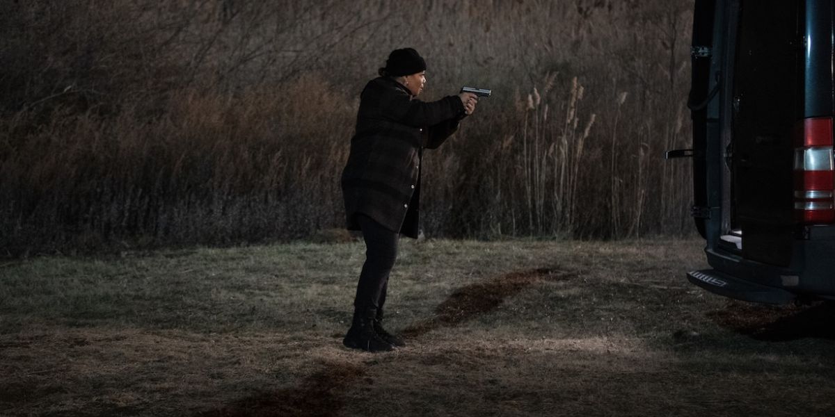 Robyn holding a gun in the middle of a field on "The Equalizer."