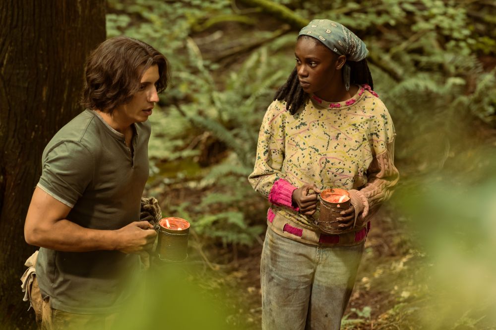Travis and Akilah walk through the woods during the day while holding mugs with candles in them on Yellowjackets Season 3 Episode 5, "Did Tai Do That?"