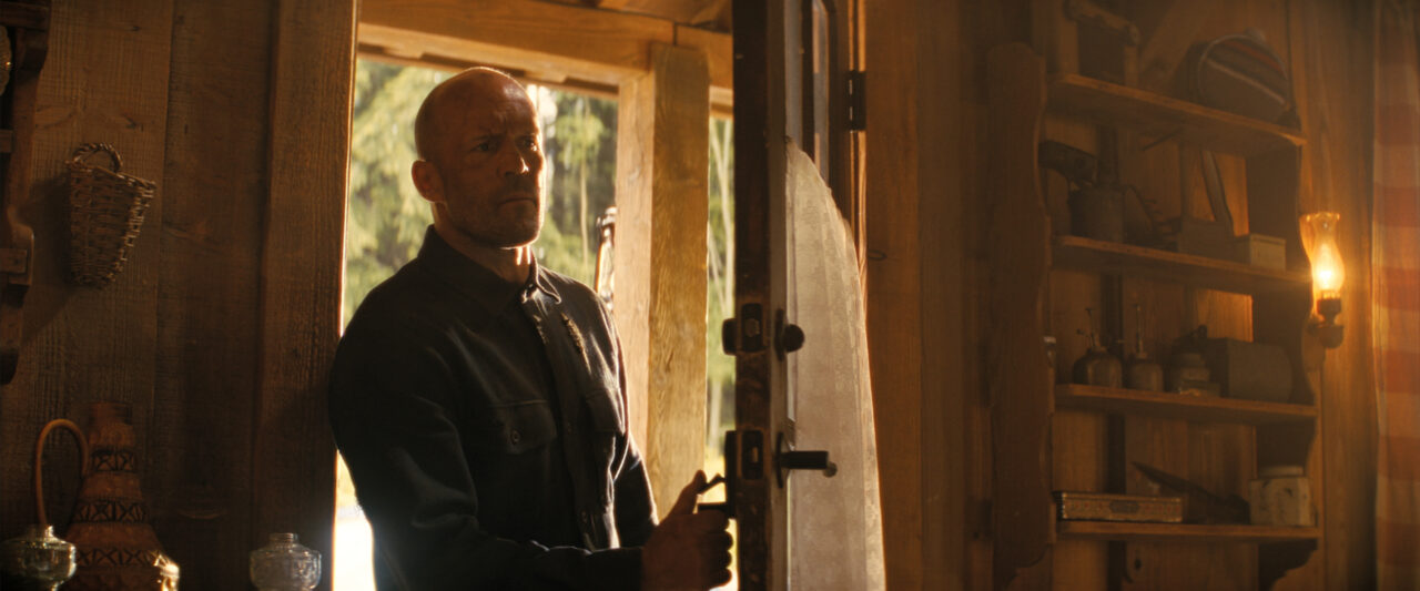 Jason Statham enters a room from outside through a front door in the film A Working Man.
