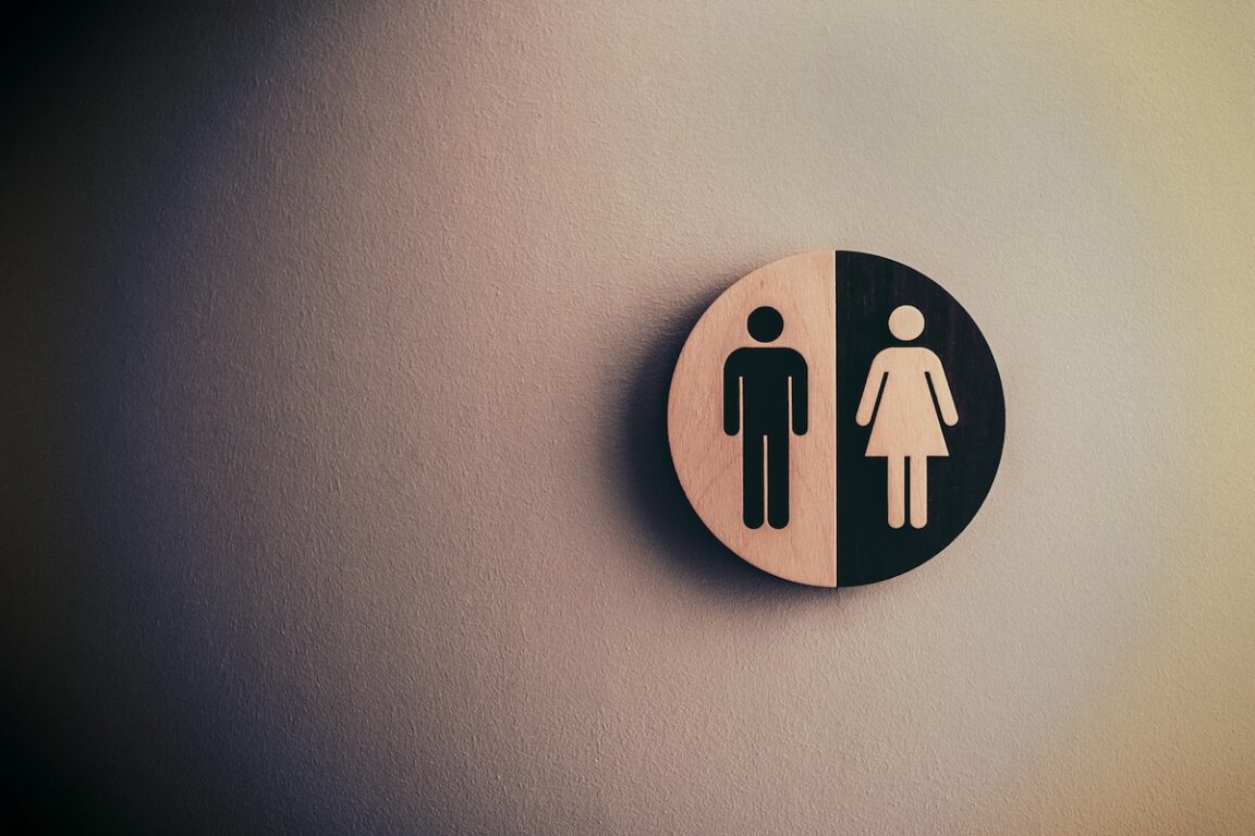 a round bathroom sign showing both female and male