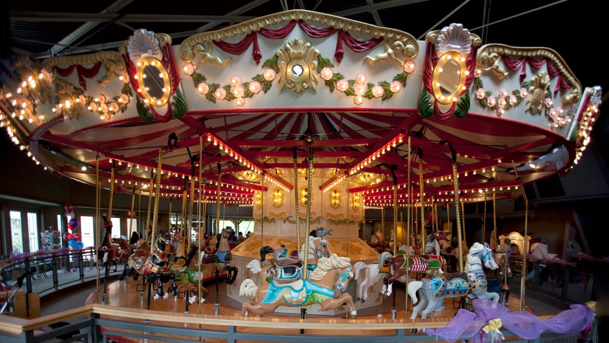 Fully restored carousel at Burnaby Village Museum. Carousel is pictured lit up from one side and is shown at its full height. The horses are riderless.