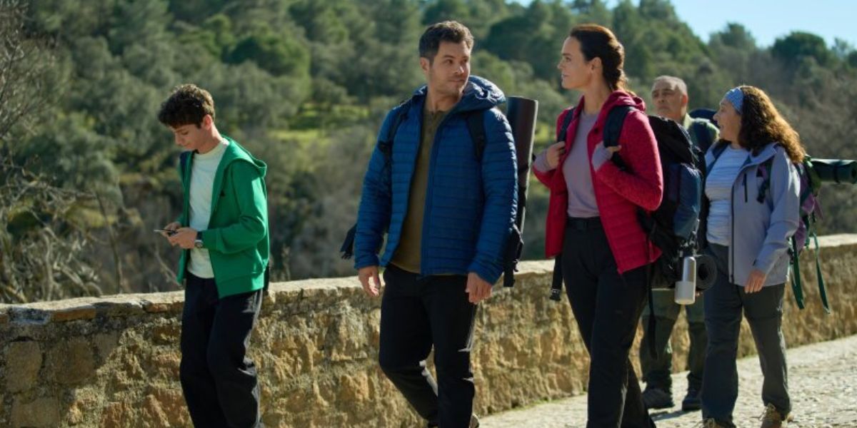 A couple walking a path with a teenage boy and other people behind them.