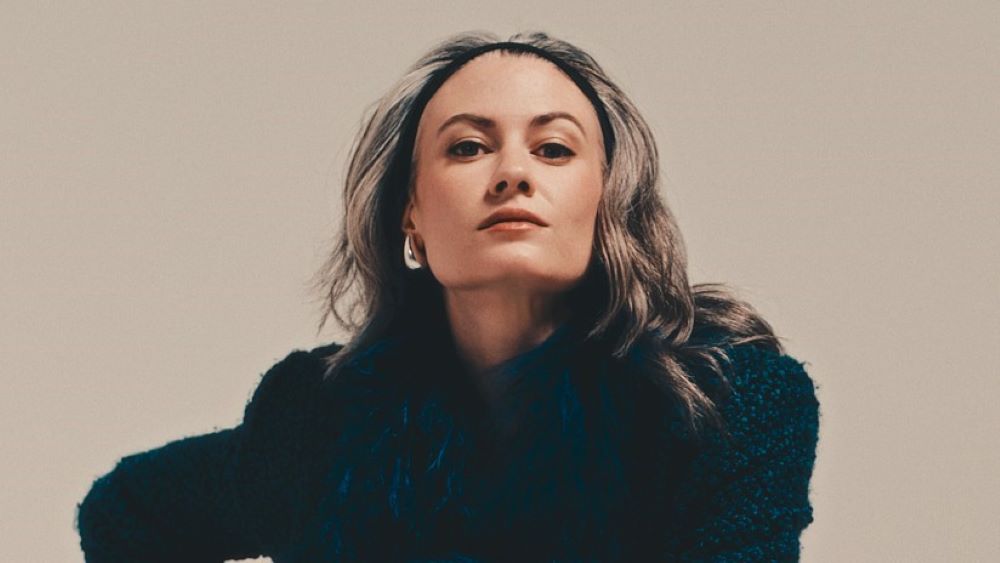Close up of Kathrine Barnes wearing a dark wool woven coat and silver earrings.
