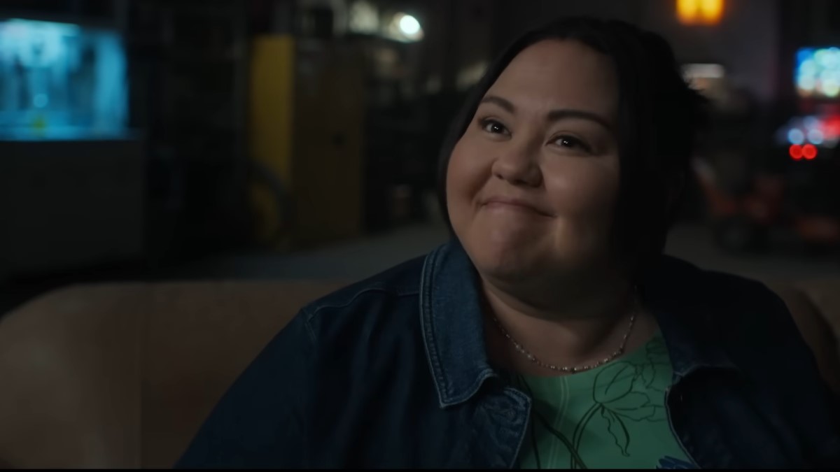 Close up of a tightly smiling Midge wearing a denim jacket over a green top on The Bondsman.