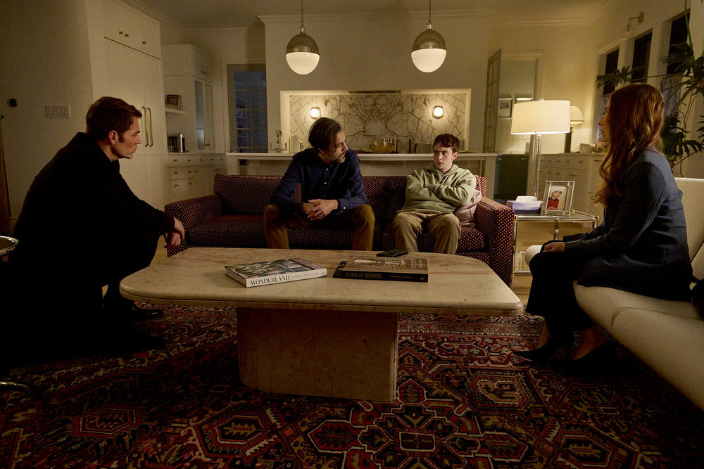 Luke, Mitch, Jaylen and Susan sit on couches and chairs in a dimly lit living room on SurrealEstate Season 3 Episode 2, "Night Terrors."