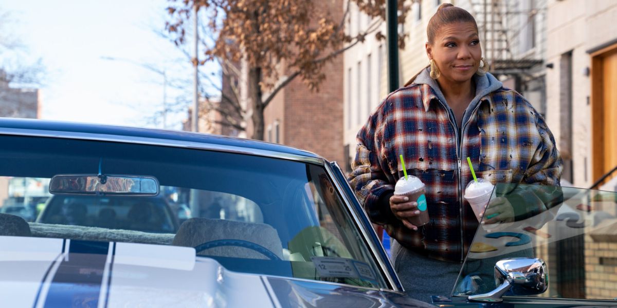 Queen Latifah as Robyn on The Equalizer standing next to a car while holding two milkshakes.