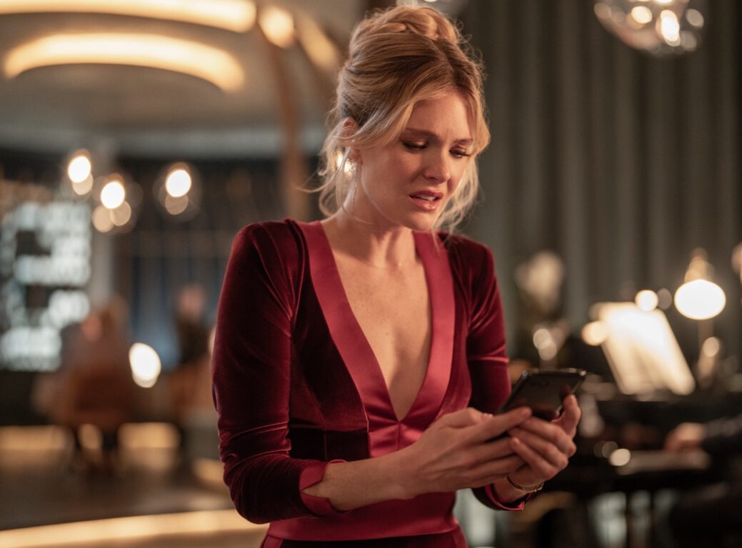 Violet (Meghann Fahy) looks at her phone in Drop