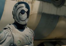 A SecUnit with its helmet on and matching armor stands alert outside a hopper on Murderbot Season 1 Episode 1, "FreeCommerce."