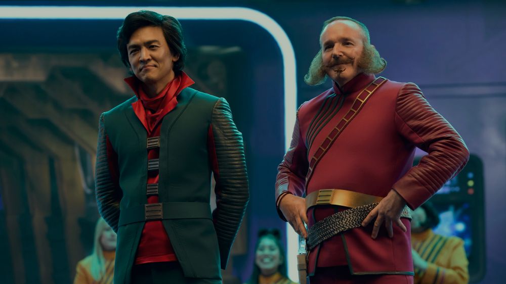 The Captain and the Lieutenant of the TV series The Rise and Fall of Sanctuary Moon stand on the bridge while smiling.