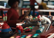 Mr. Krabs in the foreground and Uhura in the background on the bridge of the Patrick Starship Enterprise in the Star Trek: Strange New Worlds and SpongeBob SquarePants advertisement.
