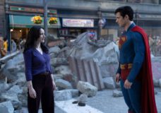 Lois Lane and Superman stand among the rubble in an outdoor shopping center during the day. Lois looks annoyed.