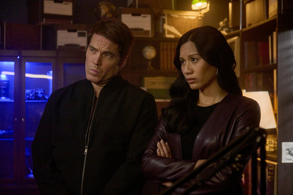 Luke and Lomax stand in a dimly lit office while looking concerned on SurrealEstate Season 3 Episode 7, "A Slice of Afterlife."