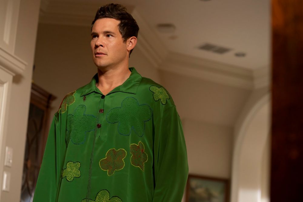 Kelvin -- a white man in his 30s -- wears a green button-down long-sleeved shirt while standing in the hallway of a house. He looks shocked.