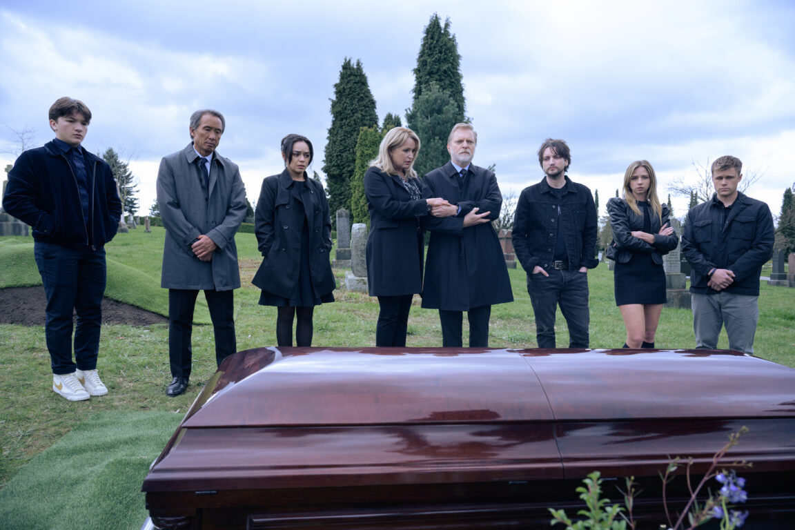 Charlie (Teo Briones), Marty (Tinpo Lee), Stefani (Kaitlyn Santa Juana), Brenda (April Telek), Howard (Alex Zahara), Erik (Richard Harmon), Julia (Anna Lore) and Bobby (Owen Joyner) gather at Iris' funeral in a cemetery during the day.