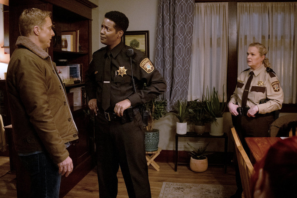 Mike and Harry chat while Liv stands opposite them in the living room of Asta and D'arcy's house on Resident Alien Season 4 Episode 10, "The End Is Here."
